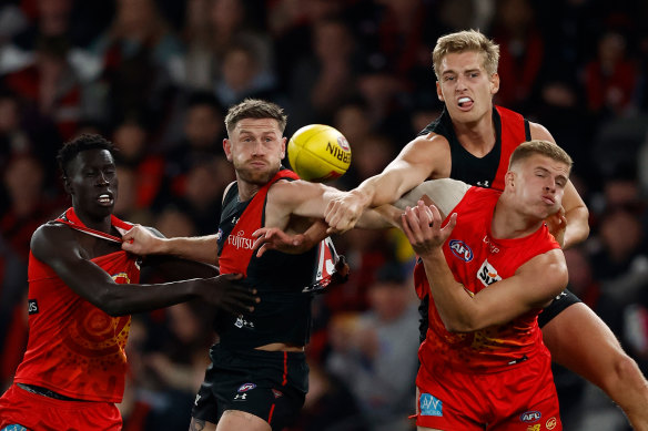 Essendon and Gold Coast players fight for the ball in a tense Marvel Stadium battle.