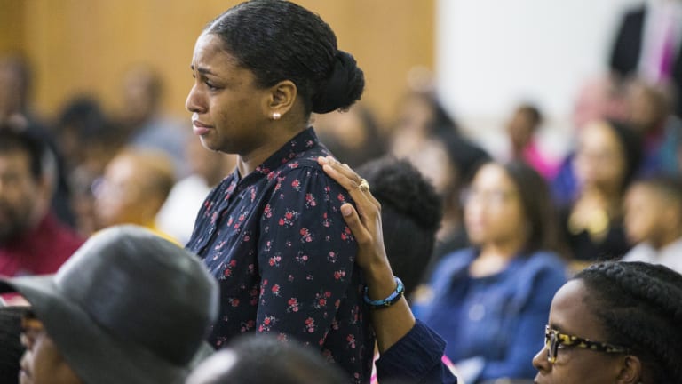 Cynthia Johnson, Botham Jean's girlfriend, stands up as she is comforted by another churchgoer during a prayer service for Jean.