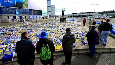 Fans look at the flowers and scarves left outside Cardiff City Stadium in tribute to Sala.