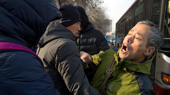 Plainclothes security officers take away a supporter of Chinese human rights lawyer Wang Quanzhang near the Secondary Intermediate People's Court of Tianjin.