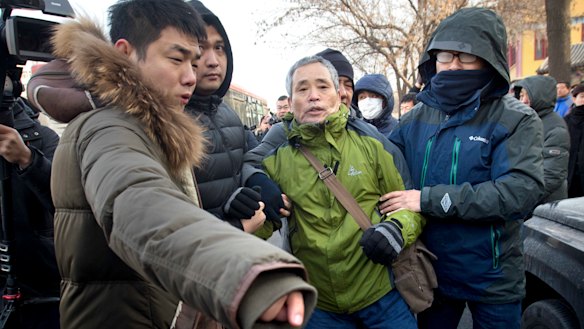Plainclothes security officers take away one of Wang's supporters.