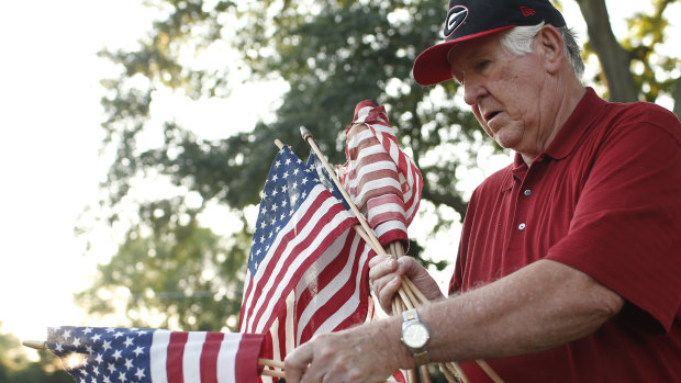 United States Air Force veteran Allen Hixon and Amvets member places a flag on a veteran's grave at Evergreen Memorial Park in Athens, Georgia.