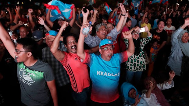 Opposition party supporters cheer and wave their party flags after Mahathir claimed victory.