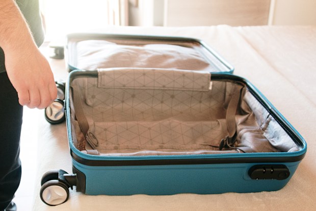 A person standing by an empty suitcase about to be packed