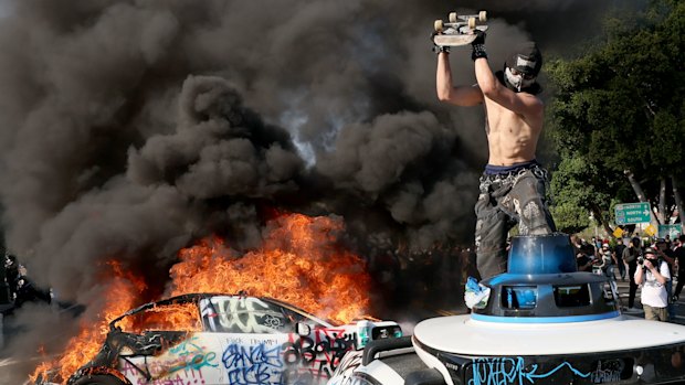 A protester damages a Waymo vehicle at Los Angeles St. and Arcadia in Los Angeles, CA on June 8, 2025.