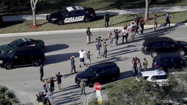 Students hold their hands in the air as they are evacuated by police from Marjory Stoneman Douglas High School in Parkland, Florida in February.