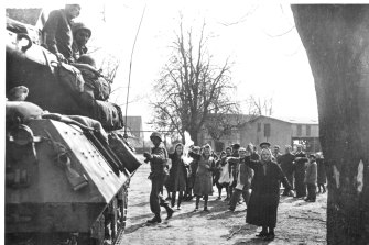 Civilians wave white flags to advancing American troops in March 1945.
