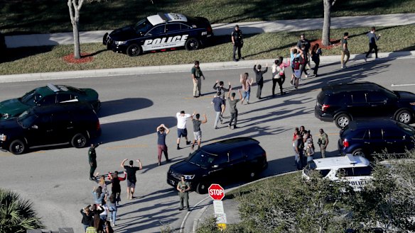 Students hold their hands in the air as they are evacuated by police from Marjory Stoneman Douglas High School in Parkland, Florida in February.