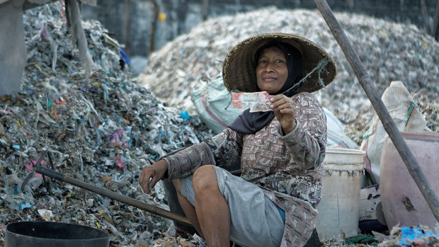Misna, a trash picker from Ploso village in East Java, holding an Australian $20 note she found among the rubbish from the local paper company.