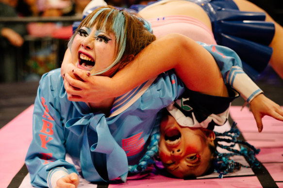Baby Face and Saki Bimi wrestling during a Sukeban match, a unique form of Japanese wrestling that mixes fashion and theatrics.