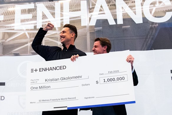 Swimmer Kirstian Gkolomeev picks up his cheque for $US1 million after breaking the men’s 50m freestyle world record as part of an Enhanced Games documentary. 