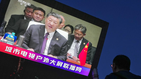 A man watches a large screen showing CCTV broadcasting news of Chinese President Xi Jinping delivers his speech at the BRICS Summit held in South Africa, at an outdoor shopping mall in Beijing.