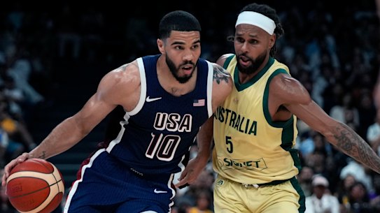 Boomers icon Patty Mills tries to defend US star Jayson Tatum on a drive to the basket.