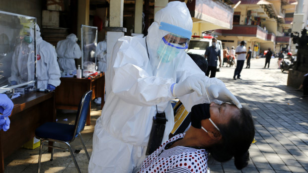 A health worker takes a nasal swab sample during public testing for the coronavirus in Bali, Indonesia.