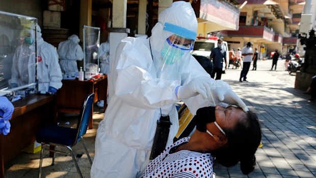 A health worker takes a nasal swab sample during public testing for the coronavirus in Bali, Indonesia.