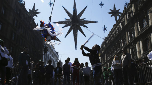 A girl hits a traditional Christmas “pinata”  filled with fruit and candy during Epiphany, or Three Kings Day, January 6, celebrations at the Zocalo in Mexico City.