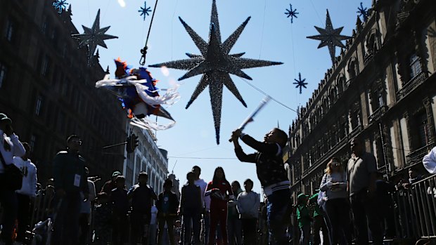 A girl hits a traditional Christmas “pinata”  filled with fruit and candy during Epiphany, or Three Kings Day, January 6, celebrations at the Zocalo in Mexico City.