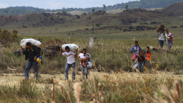 Venezuelans walk into Brazil through a field, in Pacaraima, Roraima state, Brazil.