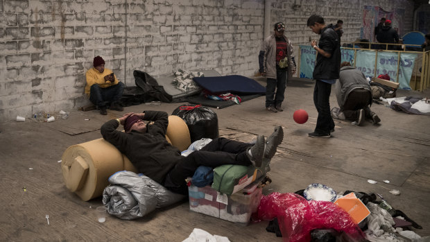 A migrant from Honduras rests on top of his belongings inside an empty warehouse used as a shelter set up for migrants in downtown Tijuana. 