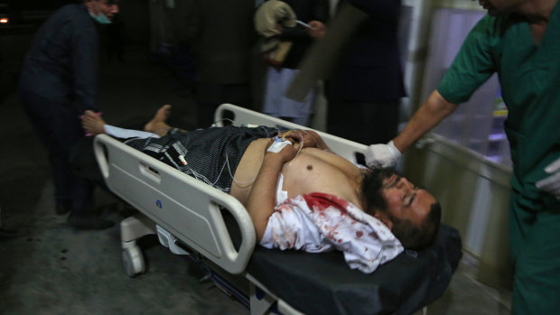 A man injured in a suicide bombing at a gathering of scholars is brought into a hospital in Kabul.
