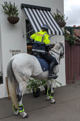 A mounted police officer stops to pick up a coffee in Brunswick, Melbourne on Tuesday.