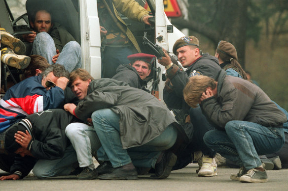 A Bosnian special forces soldier returns fire in April 1992 in downtown Sarajevo as he and civilians come under fire from Serbian snipers. 