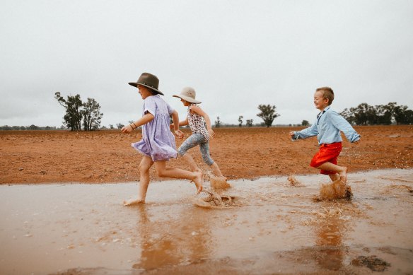 Dolly, 7, Daisy, 5, and Trader Paine, 4, enjoy some welcome rain in Narromine on Sunday. 