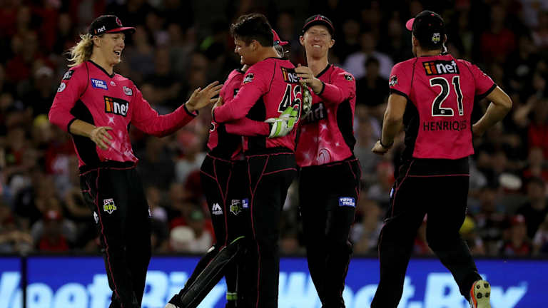 Sydney's Ben Manenti celebrates the wicket of the Renegades' Mackenzie Harvey with his Sixers teammates.