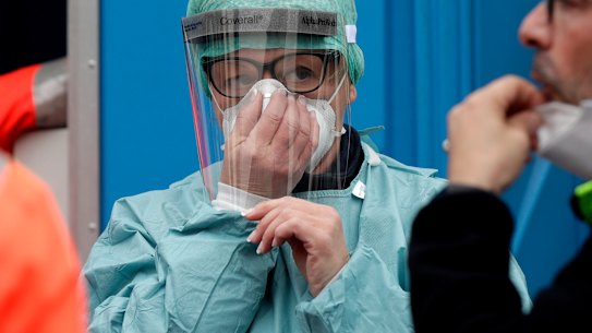 Medical staff wearing protective masks work at one of the emergency structures that were set up to ease procedures at the Brescia hospital, northern Italy.
