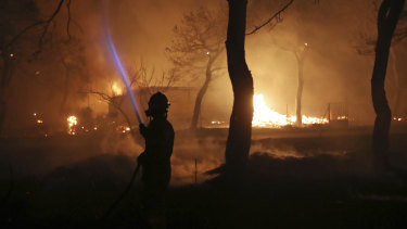 A firefighter sprays water on the fire in the town of Mati, east of Athens.