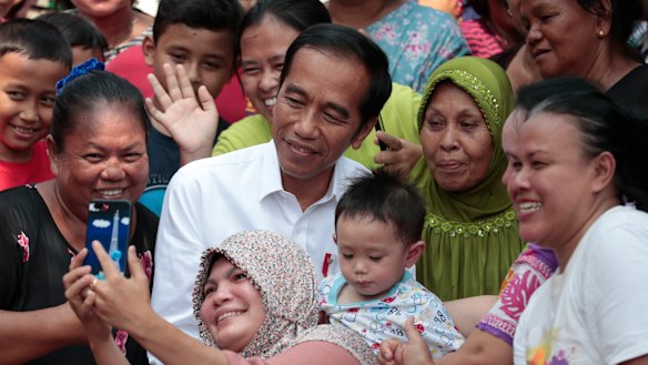 Residents take a selfie with Joko Widodo prior to a speech declaring his victory in the presidential election.