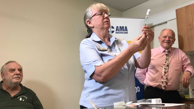 Nurse Debra Bacon prepares a COVID-19 vaccination as patient Greig Chaffey (left) and Dr Ian Williams (right) watch on.