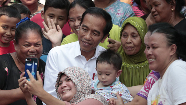 Residents take a selfie with Joko Widodo prior to a speech declaring his victory in the presidential election.
