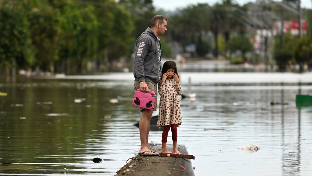 A father and daughter inspect a flooded Lismore street in March.
