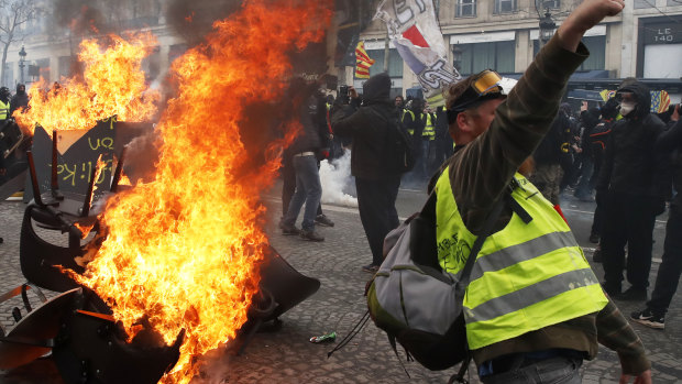 A protester shouts slogans in front of a barricade on fire during a yellow vests demonstration in Paris last month.
