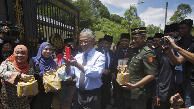 Malaysia's King Sultan Abdullah Sultan Ahmad Shah, centre, hands out food parcels to journalists camped outside the palace following the resignation of Prime Minister Mahathir Mohamad in Kuala Lumpur on Tuesday.