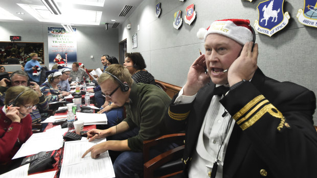 Canadian Lieutenant Major Chris Hache takes a call while volunteering at the NORAD santa tracker.