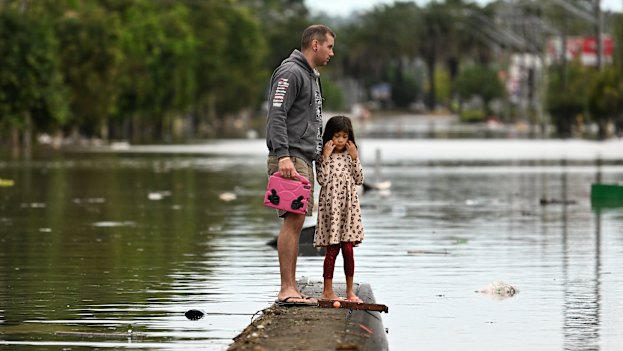 A father and daughter inspect a flooded Lismore street in March 2022.