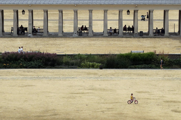 A child cycles on parched grass from the lack of rain in Greenwich Park, London.