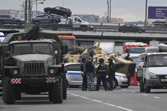 An armoured personnel carrier and police officers stand on the highway on the outskirts of Moscow on Saturday.