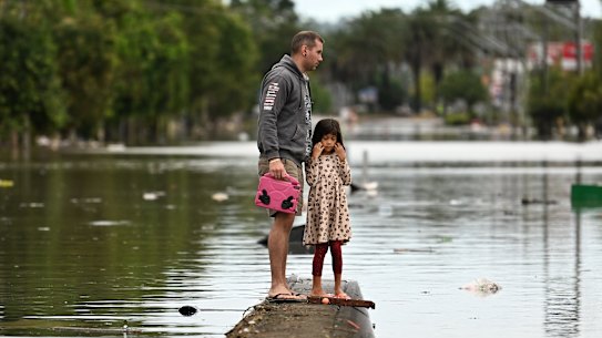 A father and daughter inspect a flooded Lismore street in March.