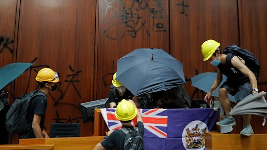 Protesters erect a Hong Kong colonial flag and deface the Hong Kong logo at the Legislative Chamber.