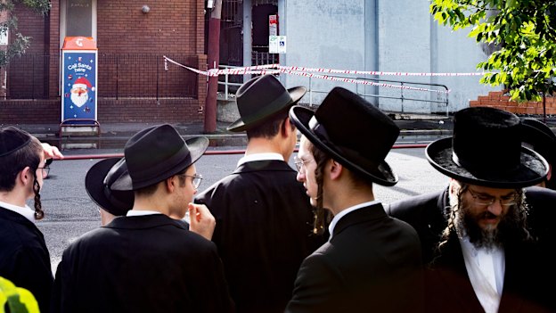Ultra-orthodox Jewish community members gather outside their burnt synagogue after Friday’s arson attack.