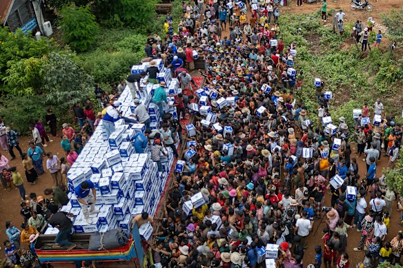 Os cambojanos deslocados recebem água no campo de reassentamento de Battkhao, na província de Odrar Meanchey, no sábado, quando um confronto na fronteira entrou em seu terceiro dia.