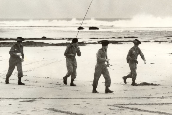 An army search party equipped with two-way radio look for Harold Holt on Cheviot Beach.