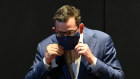 Victorian Premier Daniel Andrews puts on a face mask after fronting the media on Monday.