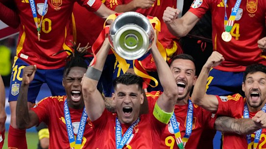 Spain’s Alvaro Morata holds the trophy as he celebrates with his teammates