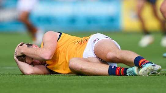 Adelaide’s Mark Keane holds his head after being concussed by Port’s Sam Powell-Pepper.