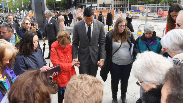 Israel Folau prays with supporters before entering mediation on Monday.