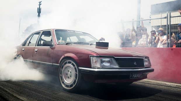 A Commodore smokes its tyres on Skid Row inside Summernats